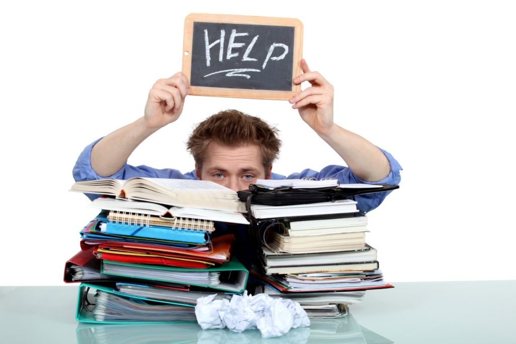 Overwhelmed college student looking over pile of books 